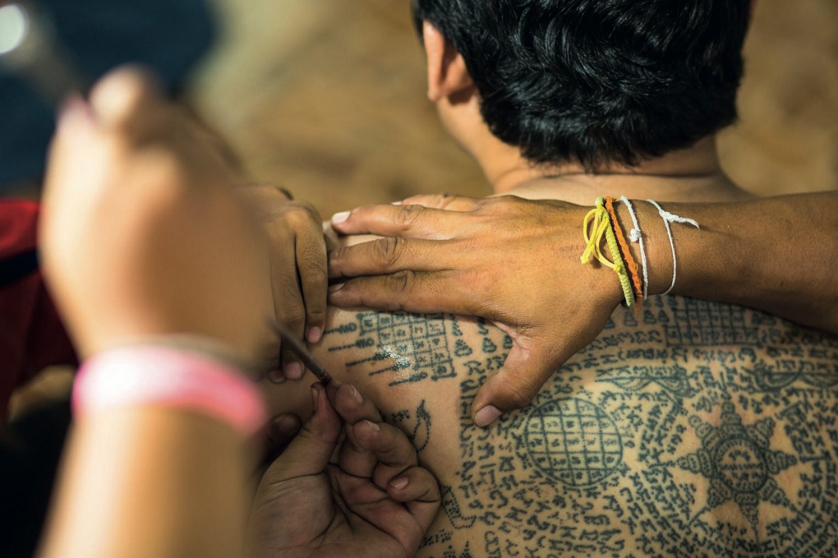 A monk tattoos a customer