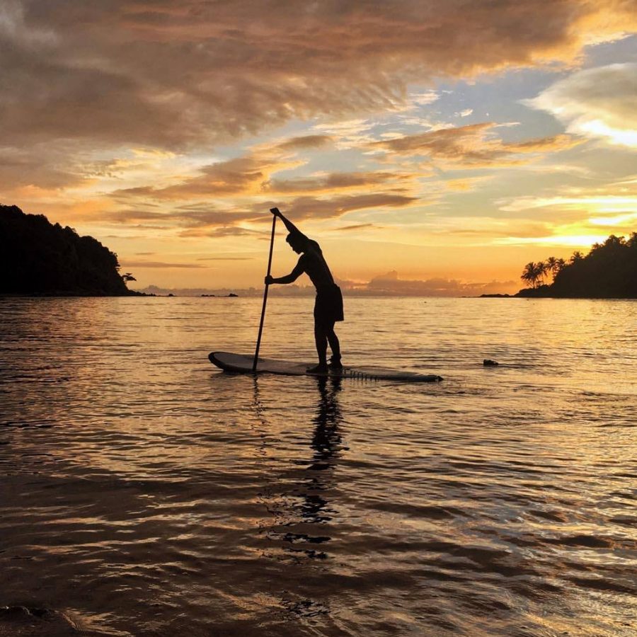 A tourist is touring the sea in Phuket on a stand-up paddleboard during sunrise