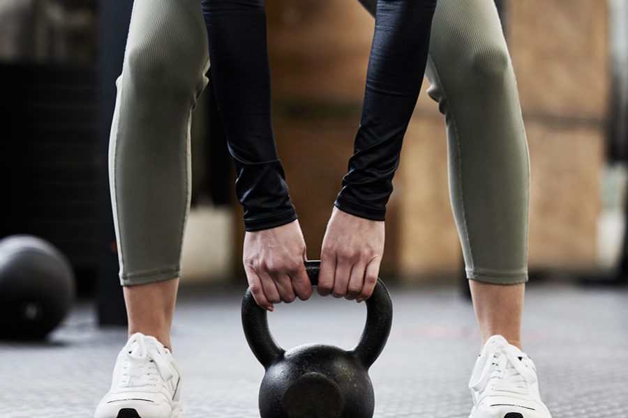 Woman picking up kettle bell. Credit: Getty Images