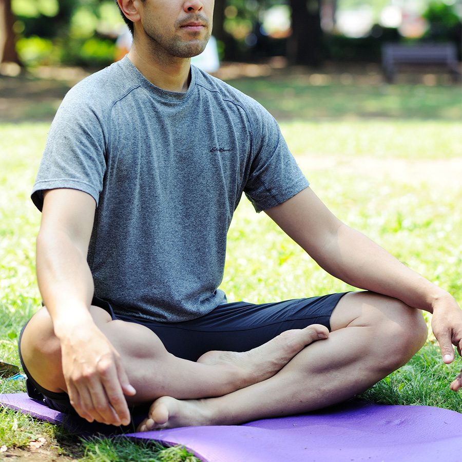 Man meditating outside on grass