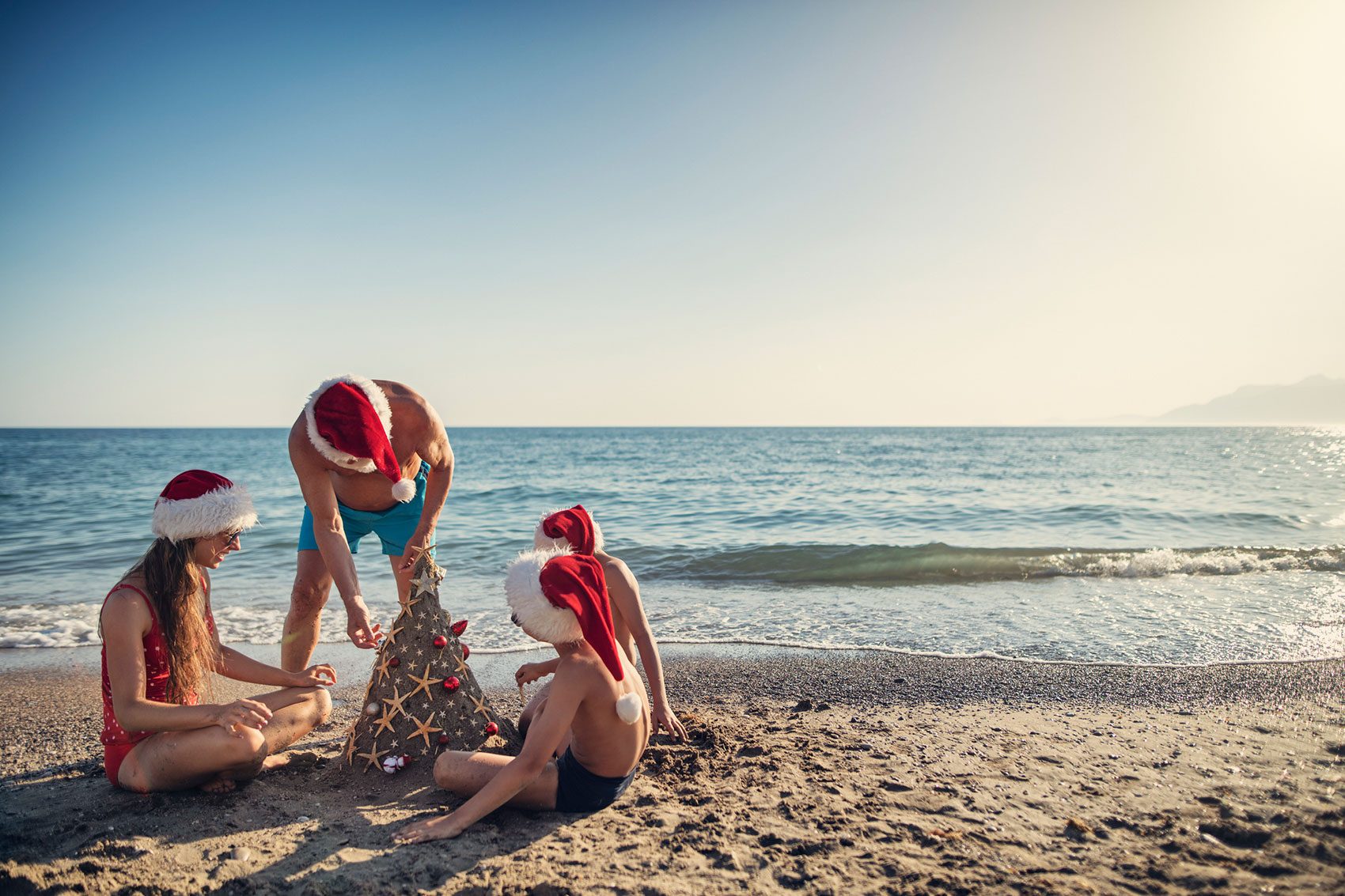 People wearing Santa hats on beach. Credit: Getty Images