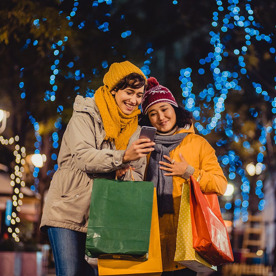 Couple with shopping bags under Christmas lights. Credit: Getty Images