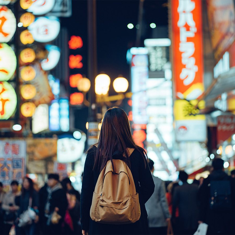 Person walking down street in Tokyo with bright neon lights surrounding them
