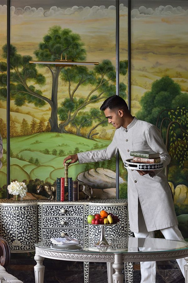 Raffles Udaipur Butler adjusting book on shelf