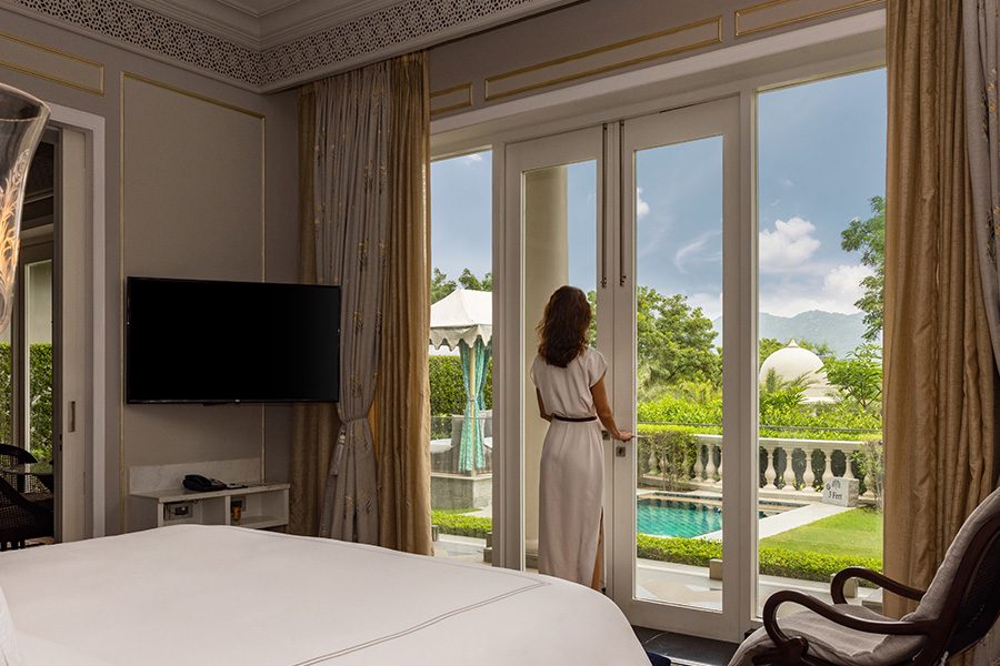 Woman looking out of hotel room window over the gardens at Raffles Udaipur