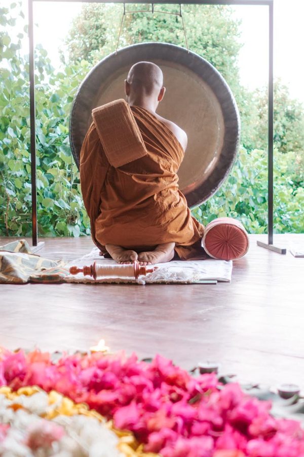 Monk kneeling in front of gong