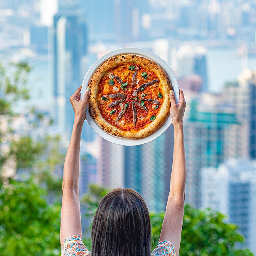 FIAMMA pizza being held up in front of Hong Kong skyline