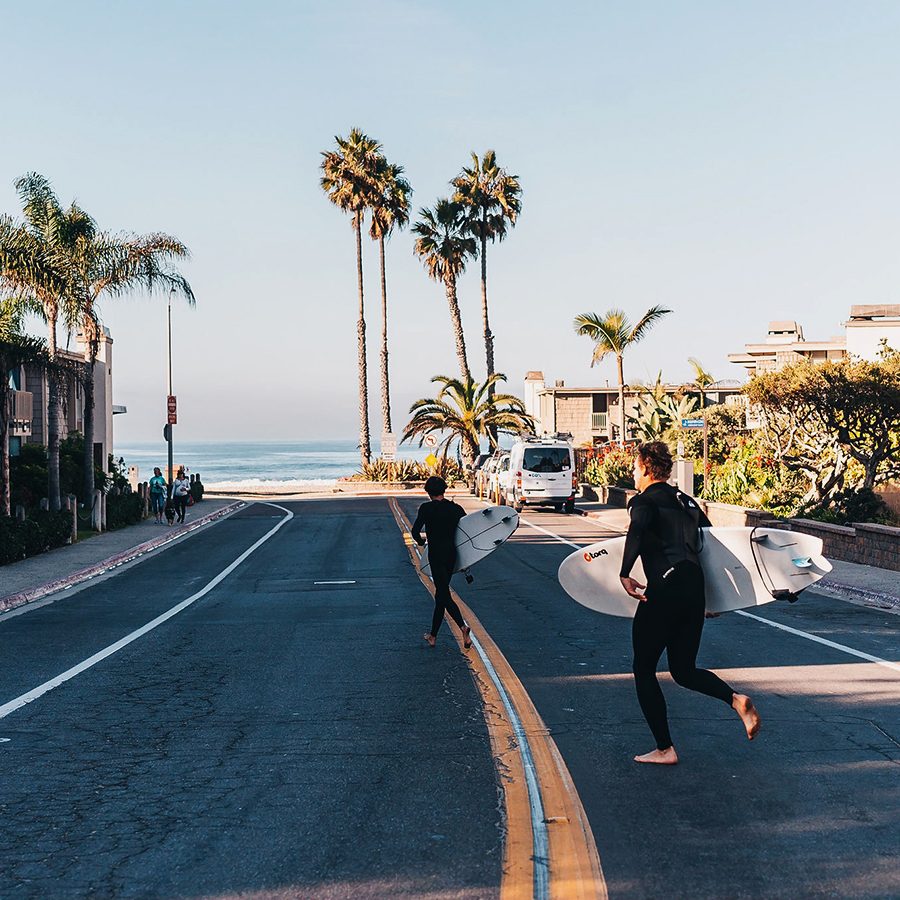 Surfers running towards water in California.