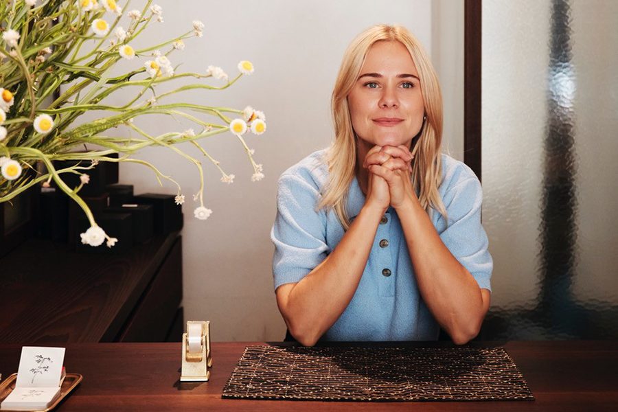 Provider Store founder Tara Bennett sitting at a wooden counter with flower decoration