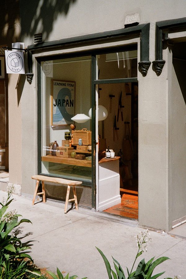 An exterior view of Provider Store storefront, glass window and wooden bench during daytime