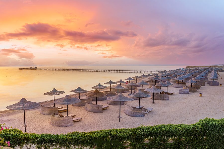 each umbrellas and cabannas lined up on a beach at sunset in Red Sea, Egypt 