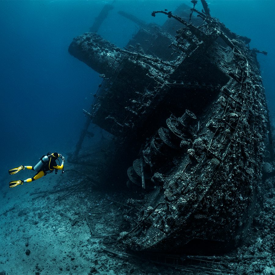  A scuba diver swimming in the ocean exploring a ship wreck underwater in Red Sea, Egypt