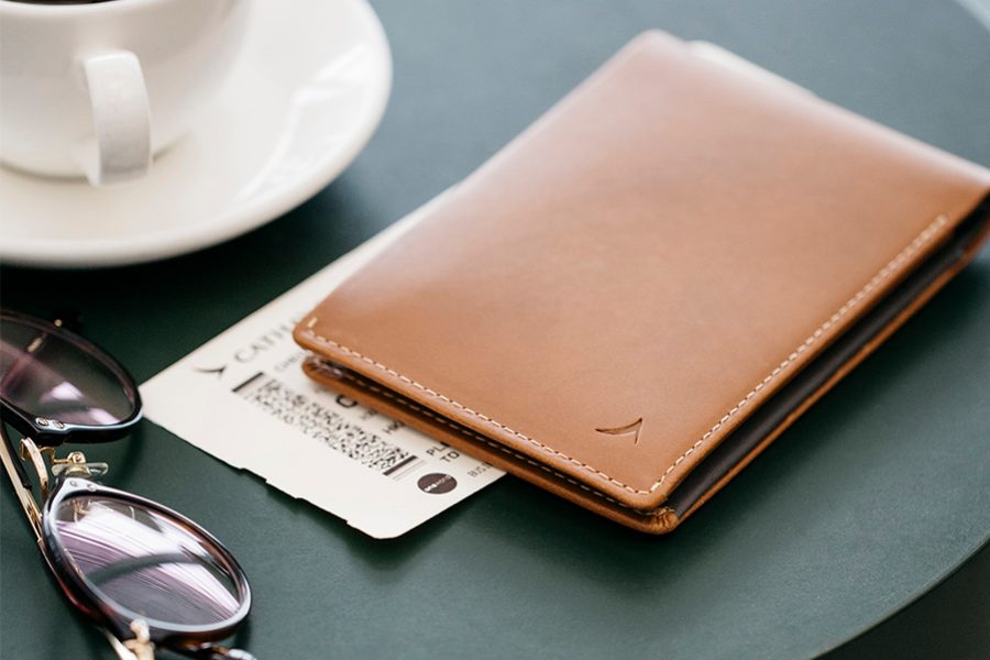 A wallet, plane ticket and sunglasses next to a cup of coffee