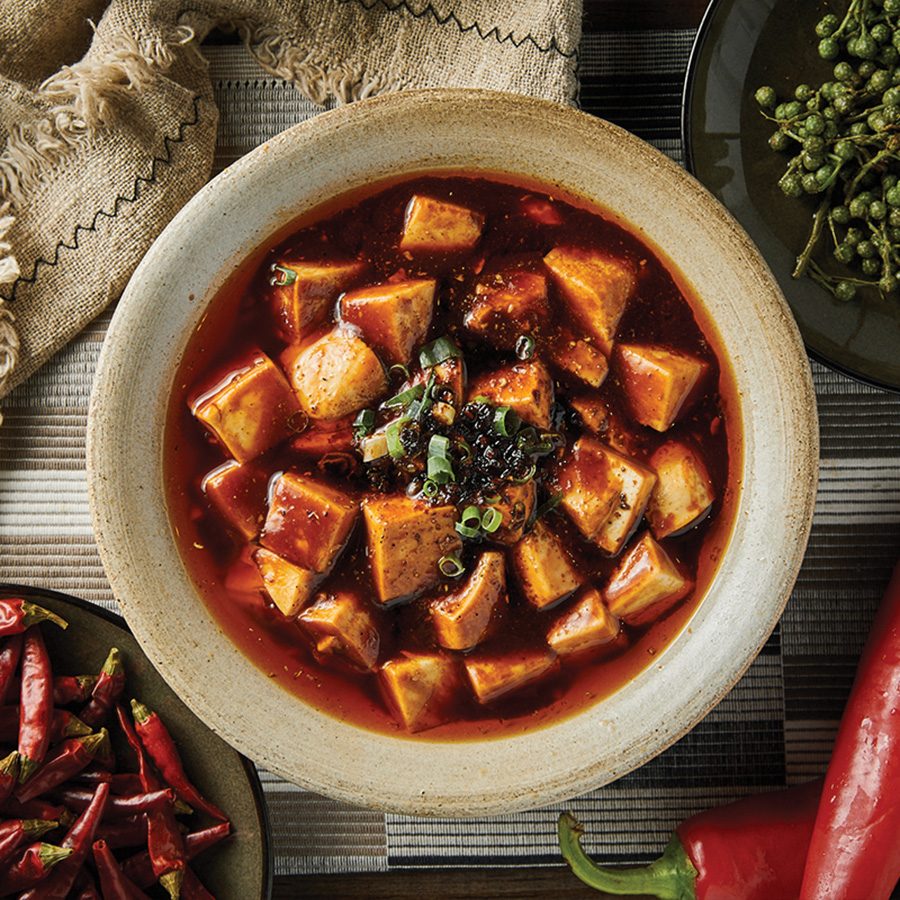 A bowl of tofu and red peppers on a table
