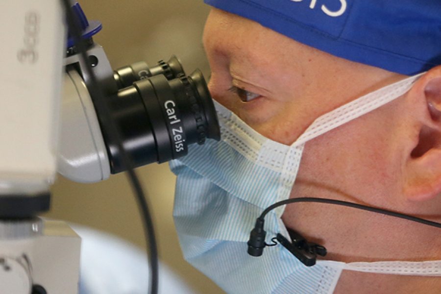A close up of a scientist looking into a microscope in a lab