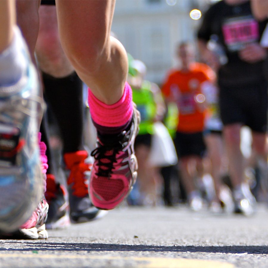 A close of of runner's shoes while racing on the road during daytime 