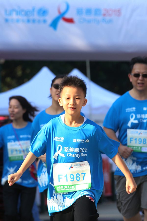 A young boy happily runs at Unicef 2023 Run for Every Child charity race