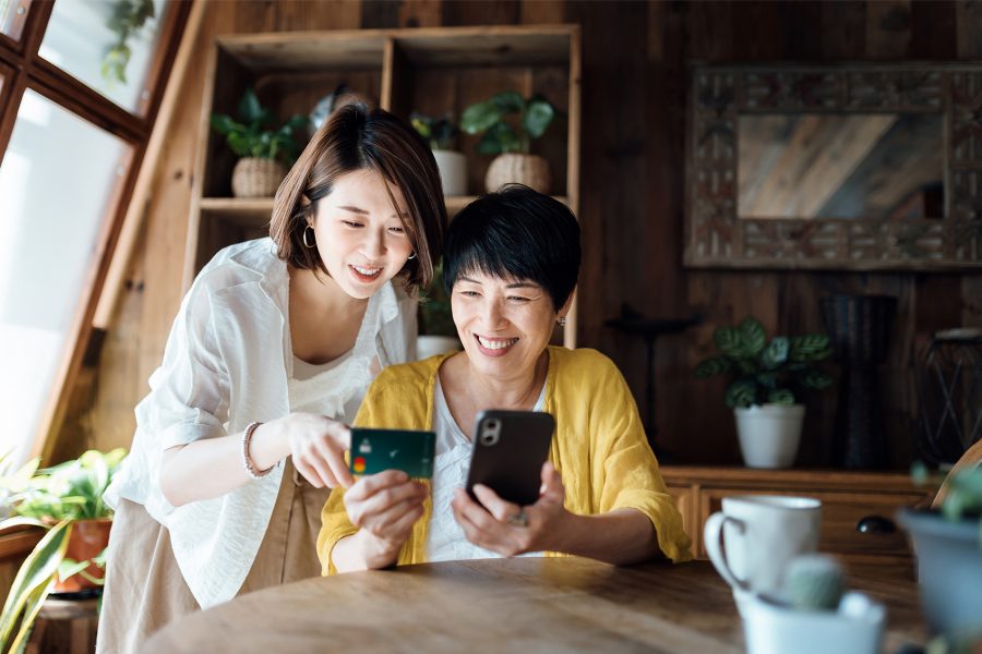 Two women using a Cathay co-branded credit card for an online payment on a smartphone