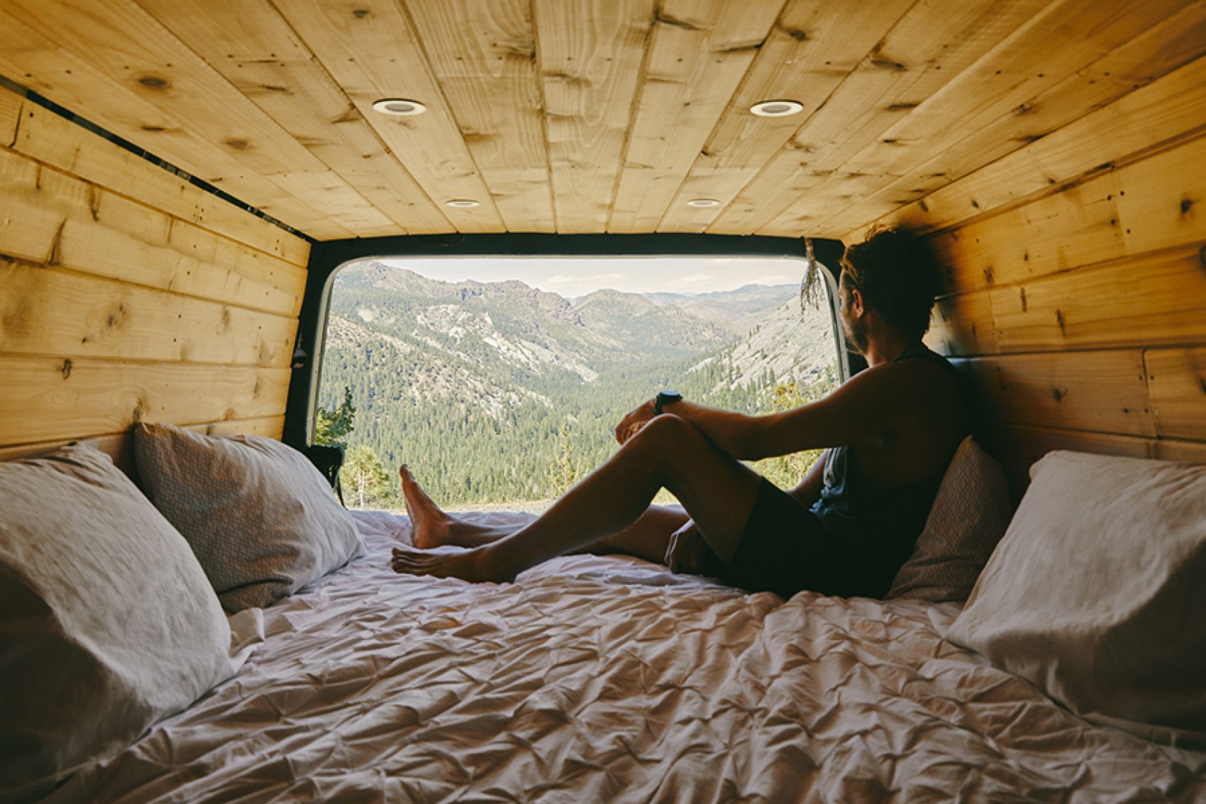 Woman in the back of a camper van looking at mountains in distance