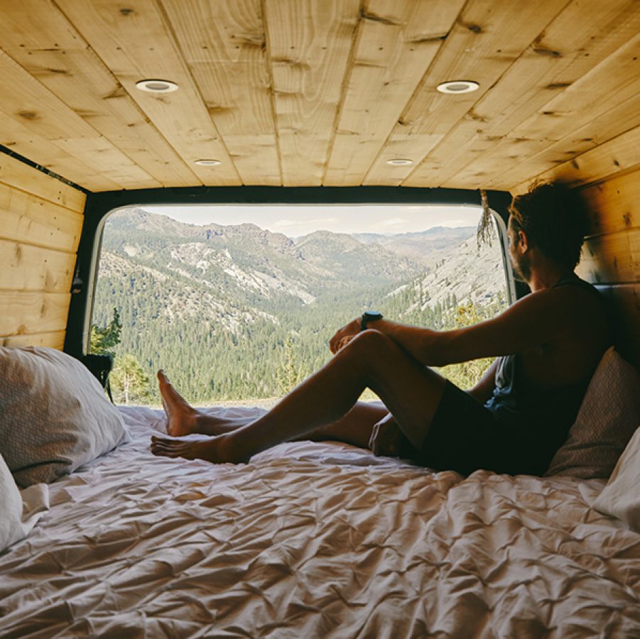 Woman in the back of a camper van looking at mountains in distance