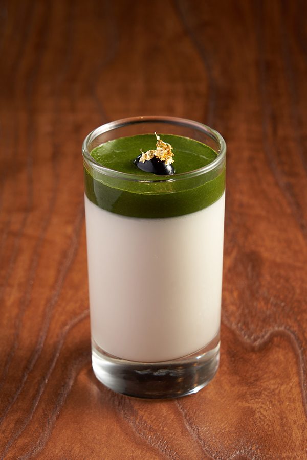 A glass filled with a white and green dessert