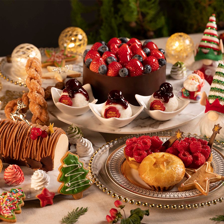 A lavish Christmas feast of Paul Lafayet deluxe Christmas hamper spread across a dining table with festive decorations, featuring Christmas cakes, cookies, pies and desserts
