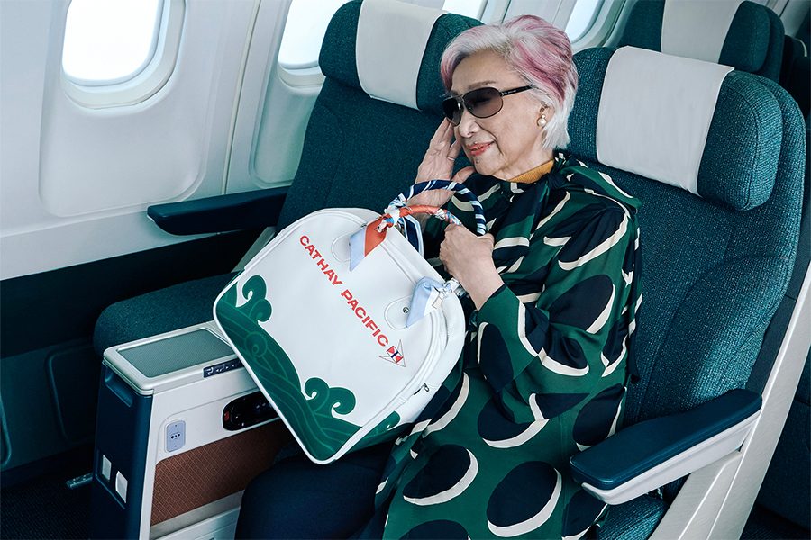 Rebecca Pan sitting in an aircraft with the Cathay Classic bowling bag in cream white