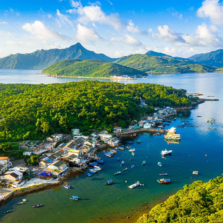 A scenic view of Tap Mun island with many boats floating in the blue sea near the shore 