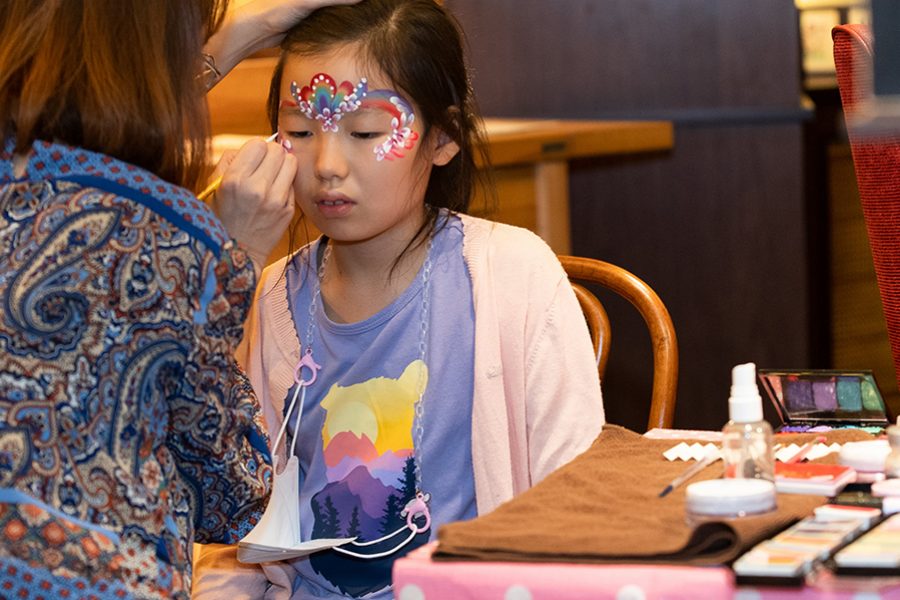 A little girl getting her face painted by a woman at The Sixteenth, Hong Kong