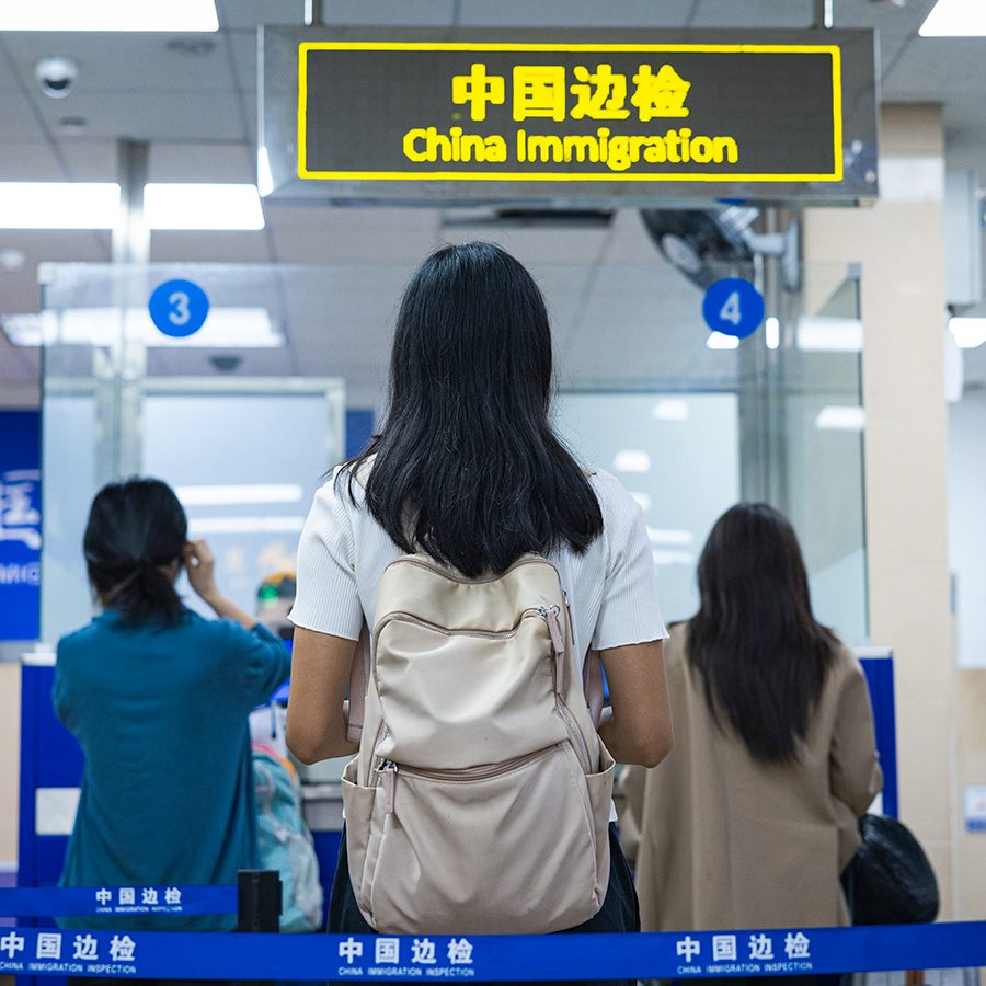 Women is waiting in front of the sign of China Immigration