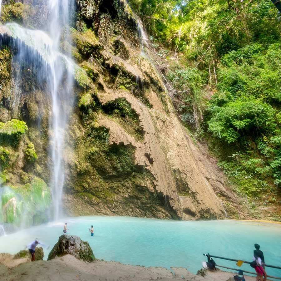 A group of people taking pictures in front of Mantayupan Waterfalls in Cebu, Philippines