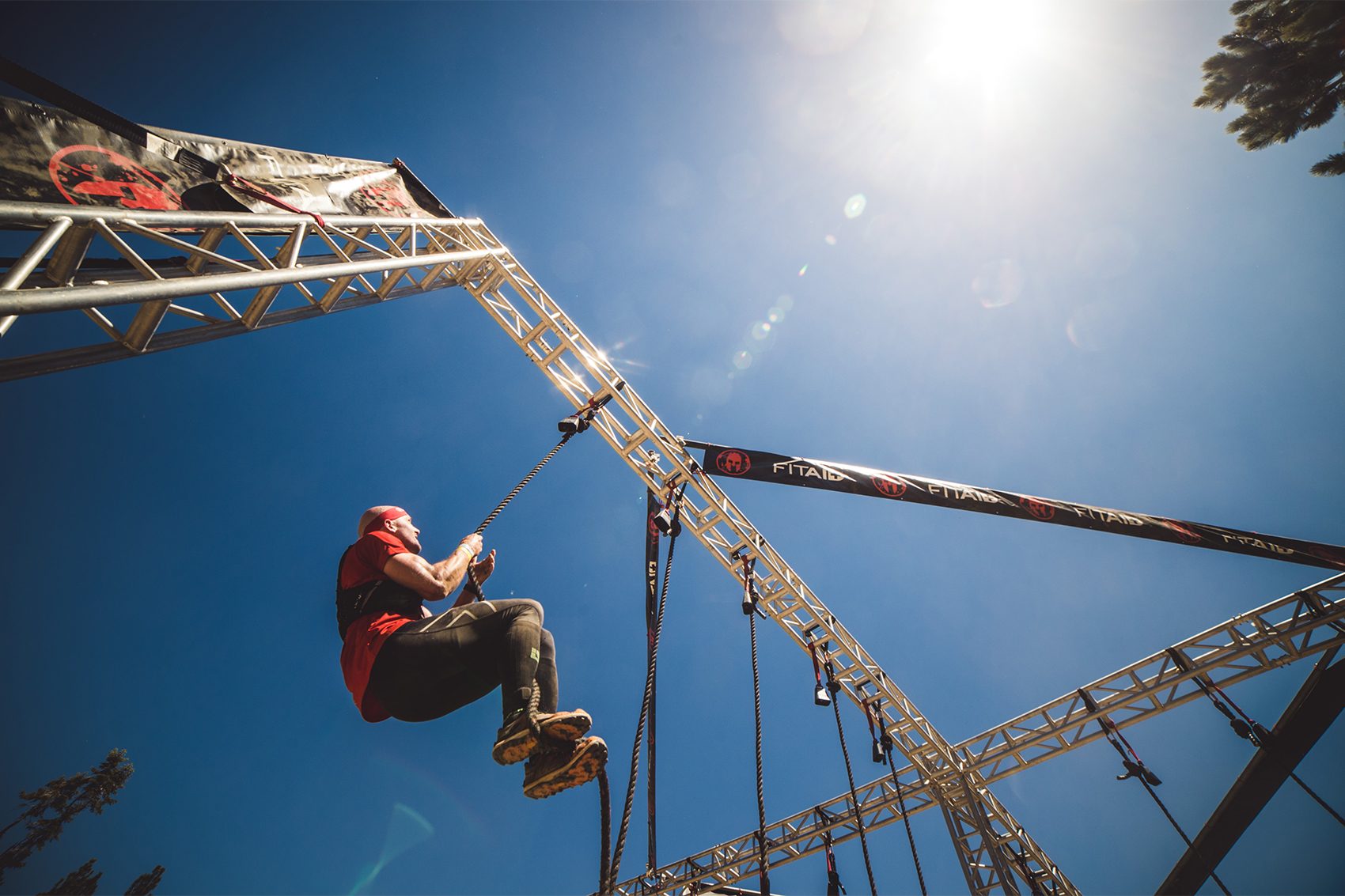A man in atheltic gear climbing up a rope during a hyrox competition at Spartan race
