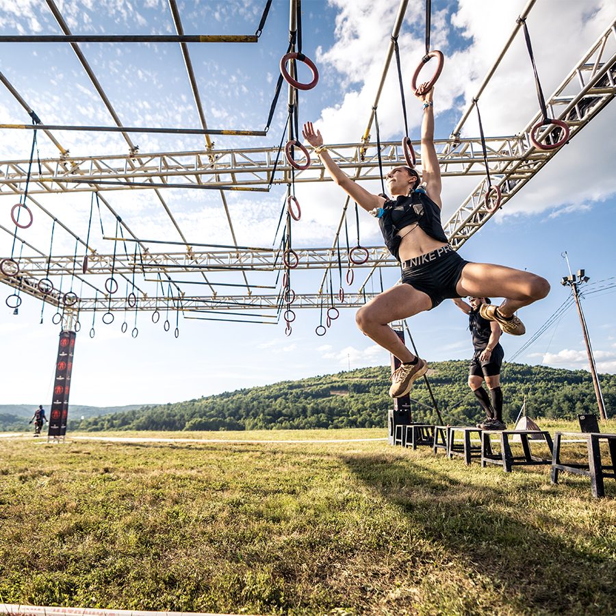 A woman swimming with rings in an obstacle course at a Spartan race