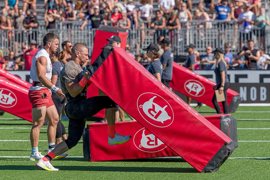 A group of men and women pushing a weighted sled across a field of grass at the CrossFit Game
