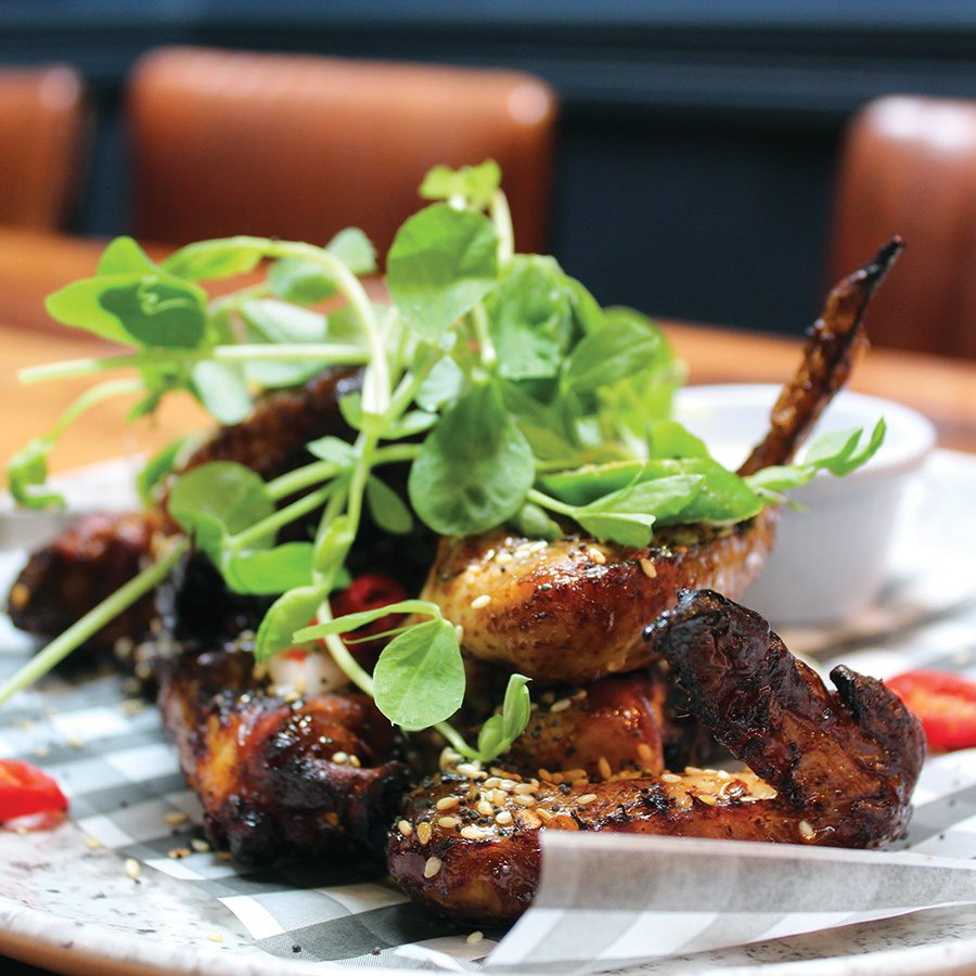 A plate of chicken wings topped with garnish