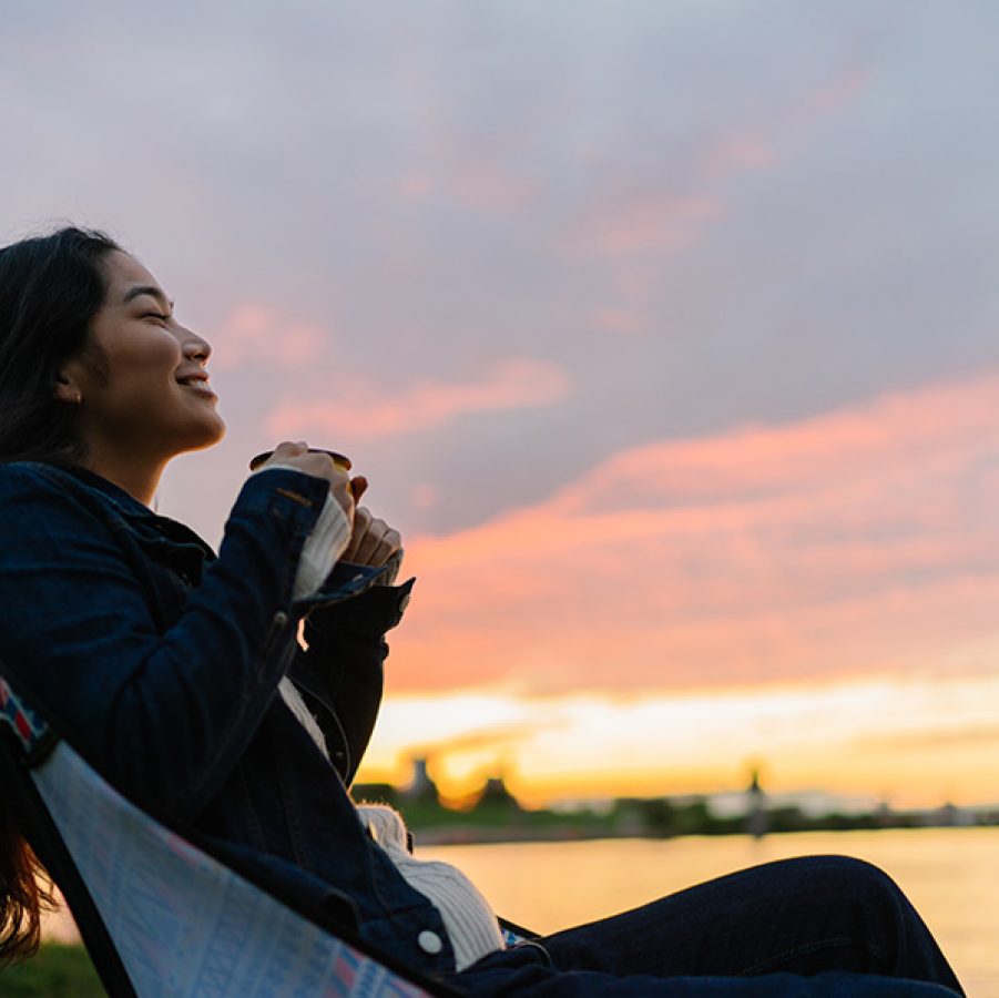 Woman relaxing by lake at sunset