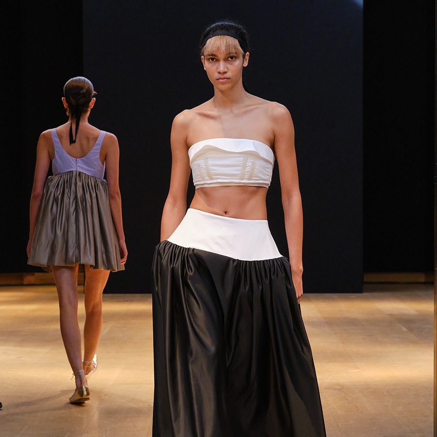 Model wearing white top and black skirt at a Molly Goddard runway