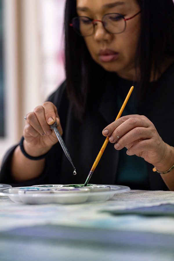 Fan Yan holding paintbrushes