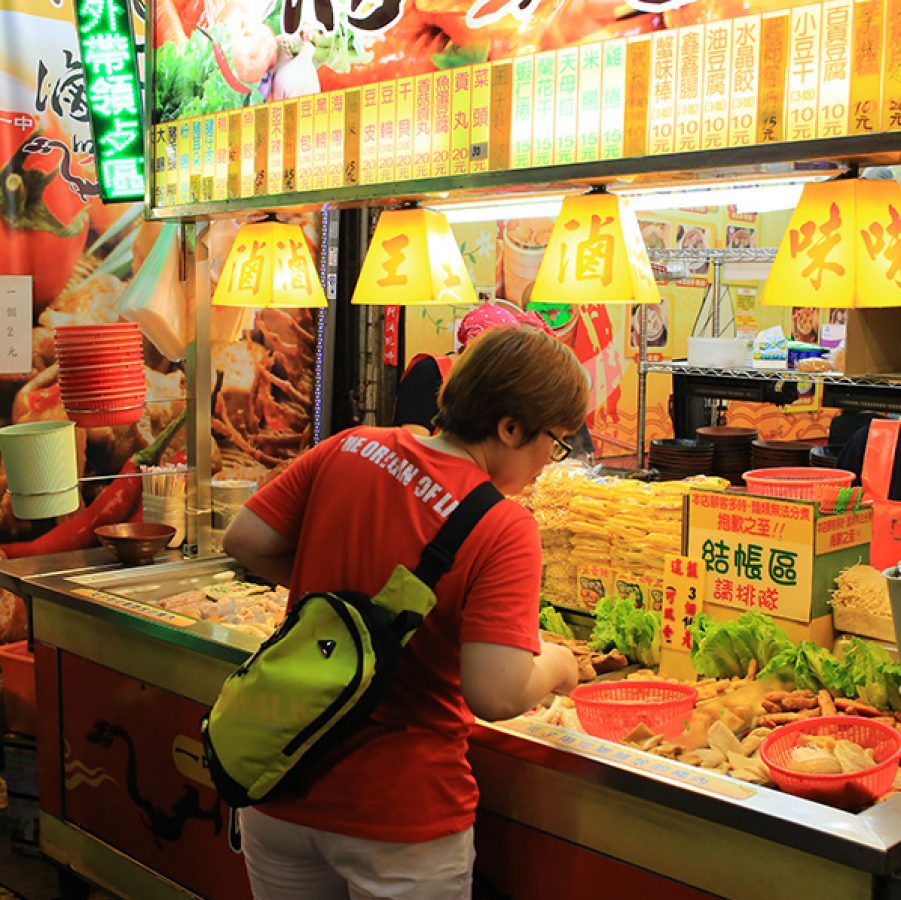 Woman browsing a food stall on Yizhong Street, Taichung