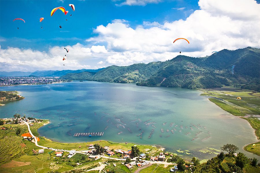 Many paragliders above Pokhara Lake, Nepal on a sunny day
