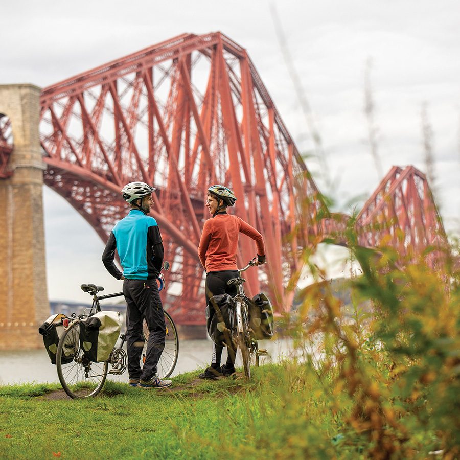 Two cyclists in front of Forth Bridge