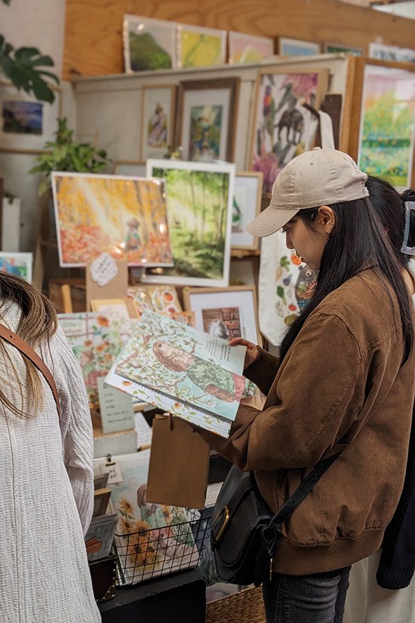 A woman looking at a picture book at the Rose Street Artists' Market