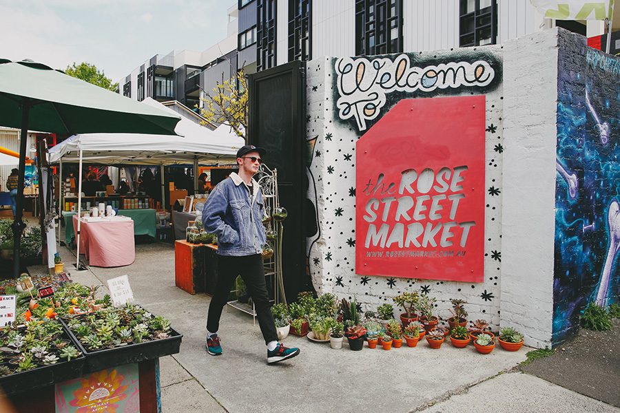 A man walking next to the Rose Street Market logo