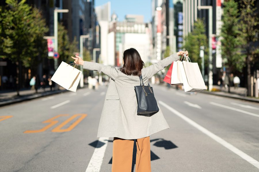 Back view of an Asian woman joyfully shopping on the street