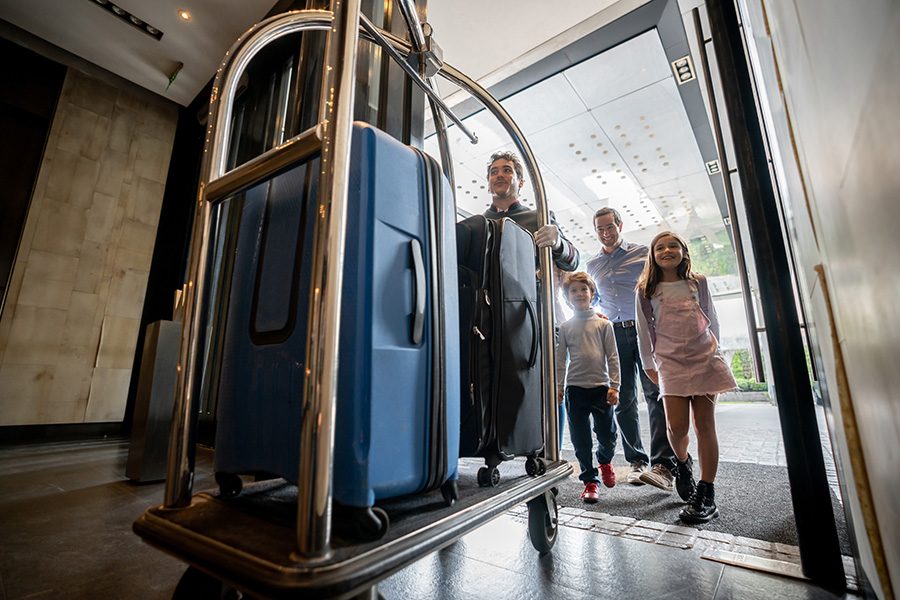 Man helping guests bring luggage into hotel
