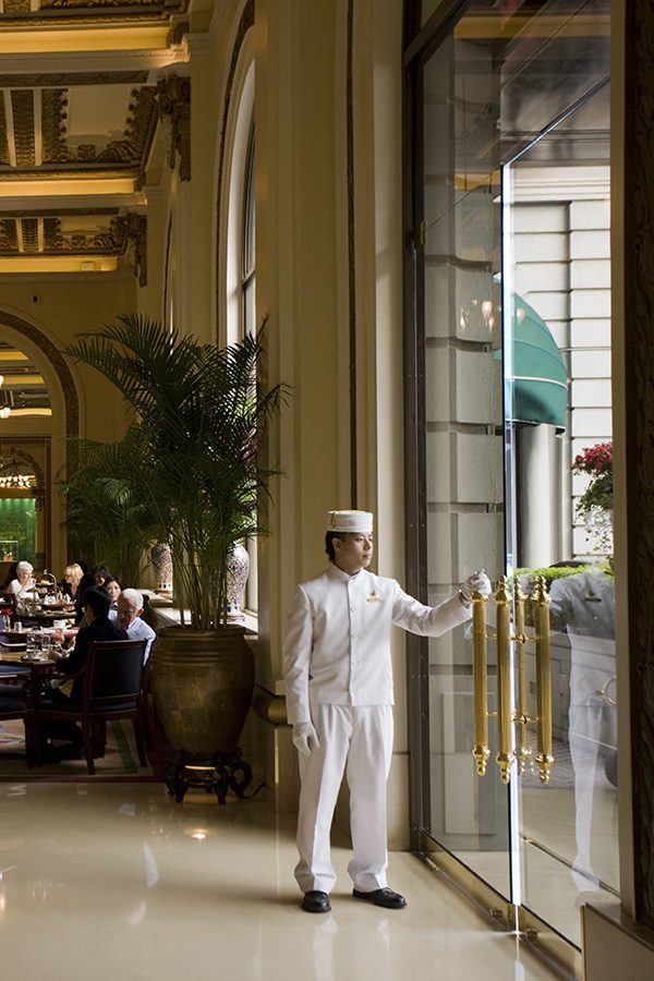 Bell boy holding a hotel door open for guests