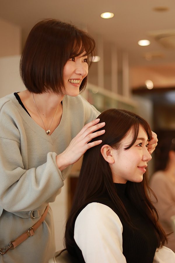 A woman getting a haircut and her hairstylist at the salon
