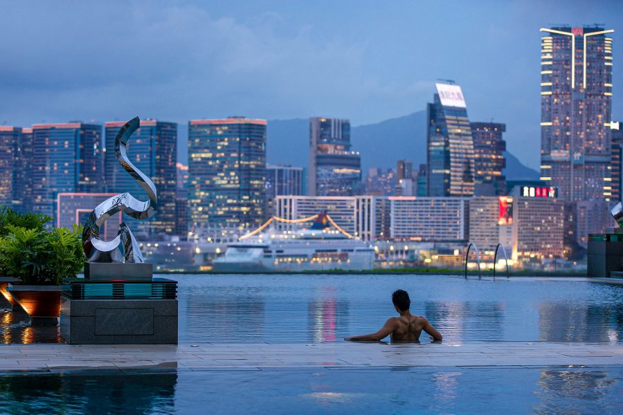 Man in a pool looking out to skyline
