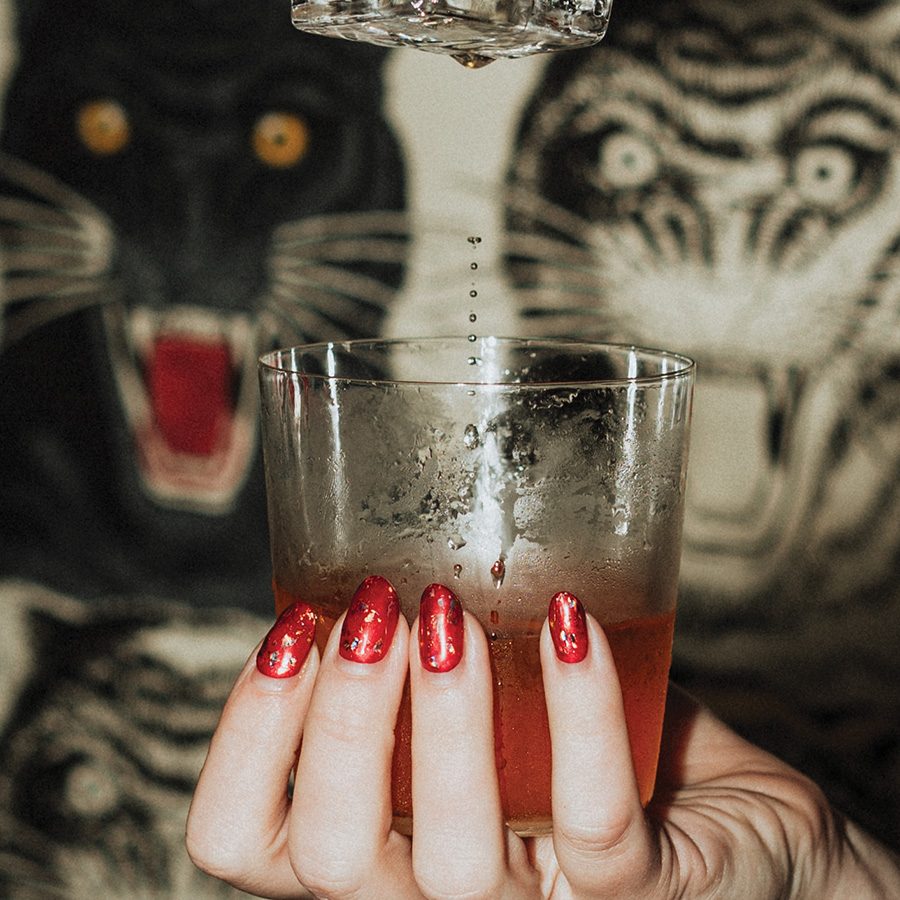 Tiger graphics behind hand holding glass