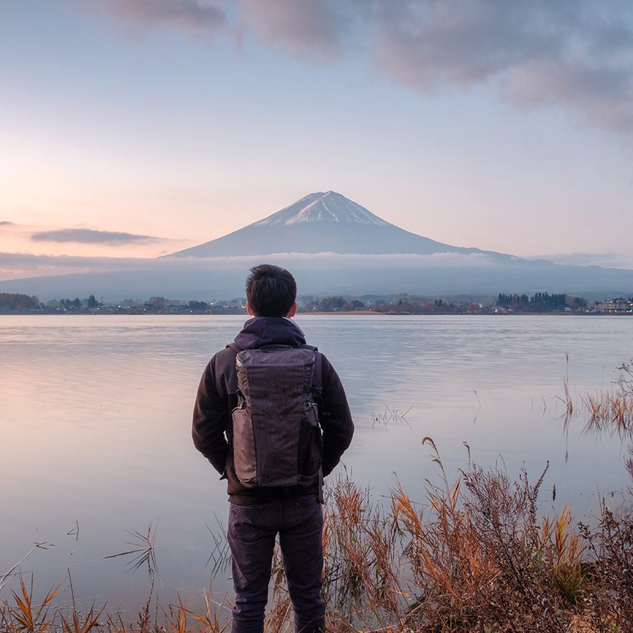 Man is looking at the mountain and facing the lake